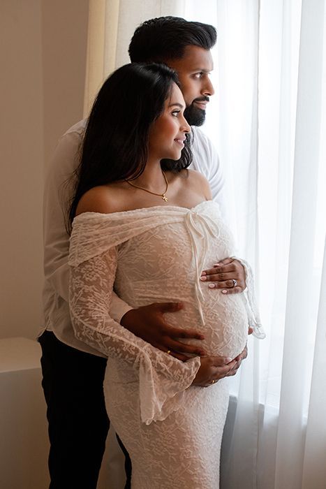 Emotionale Schwangerschaftsfotografie in Düsseldorf mit Partner: helles Studio-Setting mit sanftem Licht und liebevollem Fokus auf den Babybauch.