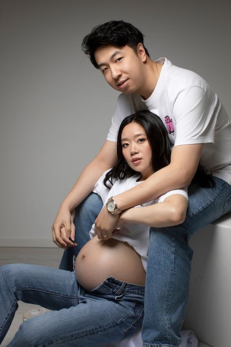 Moderne Babybauchfotografie mit Partner in Düsseldorf: authentisches Studio-Portrait eines jungen Paares mit natürlicher Pose und ruhiger Bildsprache.