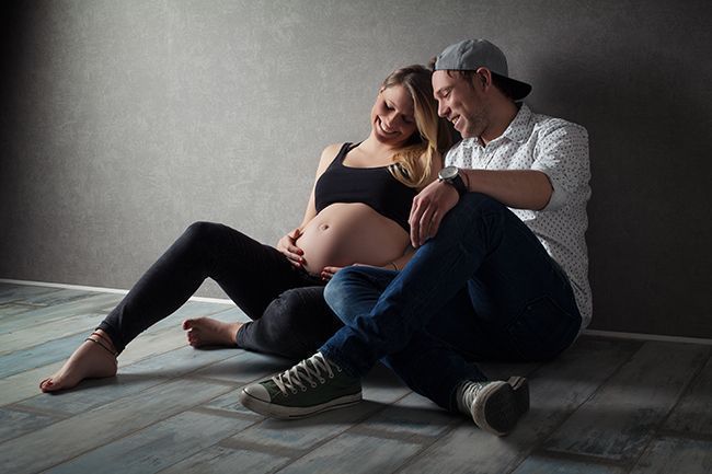 Familien-Babybauchfotografie in Düsseldorf: werdende Eltern sitzen gemeinsam und genießen den Moment der Schwangerschaft.