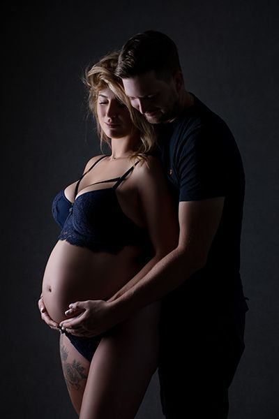 Sinnliche Babybauchfotografie mit Partner in Düsseldorf: Paar in enger Umarmung im Studio.