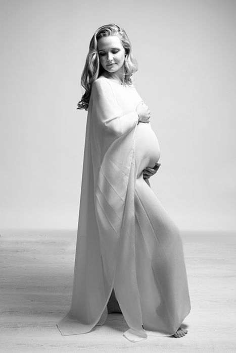 Künstlerische Schwarz-weiß Babybauchfotografie aus Düsseldorf mit stehender Pose hell und nostalgisch anmutend.