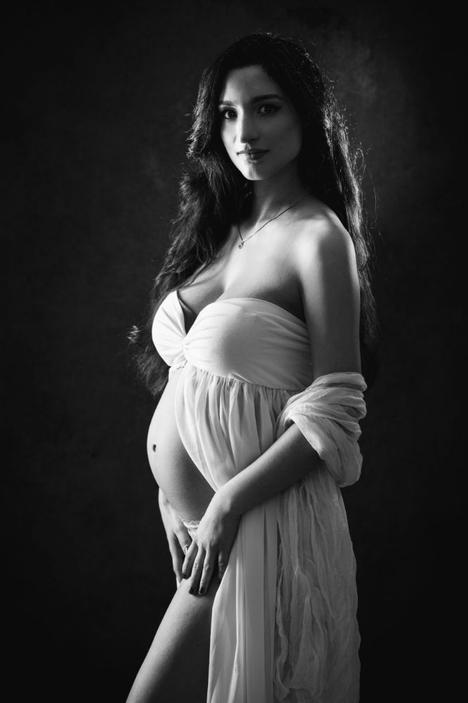 Zeitlose Schwarz-weiß Schwangerschaftsfotografie in Düsseldorf: sanftes Studio-Portrait einer werdenden Mutter mit natürlicher Pose.