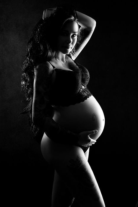 Fotografie mit dramatischer Lichtsetzung und betonter Babybauch-Silhouette.