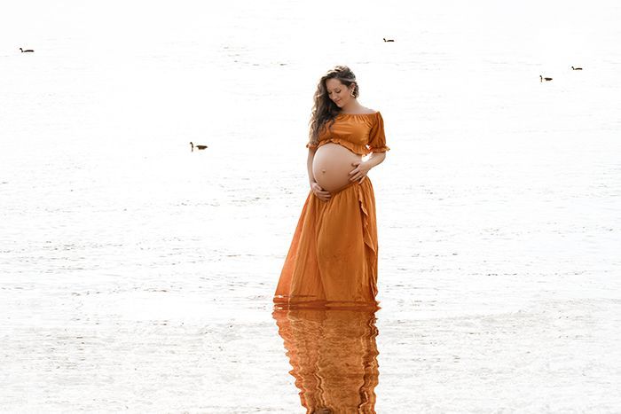 Mutter steht im weiten Feld bei weichem Licht in Düsseldorf.