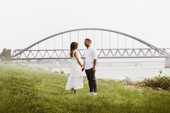 werdende Mutter steht im Gras mit natürlichem Licht und ruhiger Stimmung.